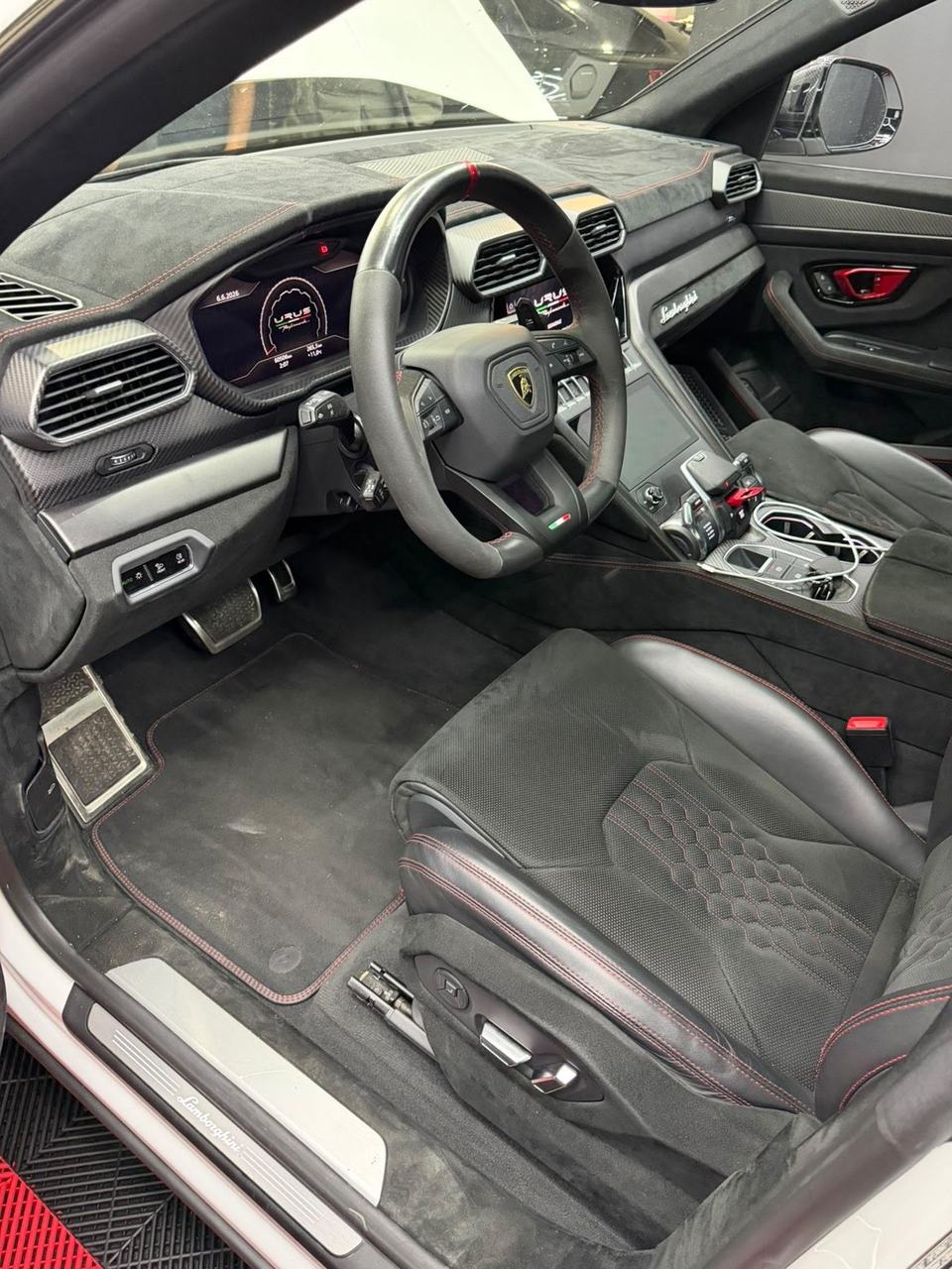 Habitacle de la Lamborghini Urus avant nettoyage : tapis poussiéreux et seuil sale